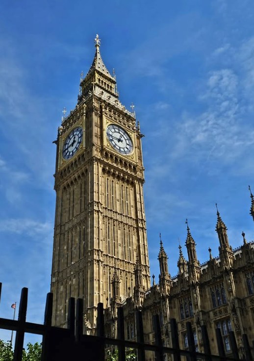 The Elizabeth Tower seen from Parliament Square through the perimeter railings, with the pinnacles of the Palace to its right